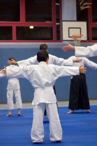 UuM_1 Aikidoka beim Aufwärmen mit ausgestreckten Armen in der Turnhalle